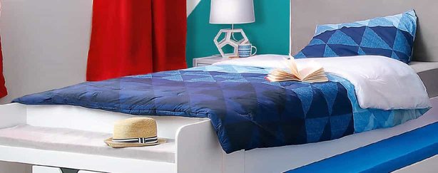 A bed with bedding and linen in various of shades of blue.