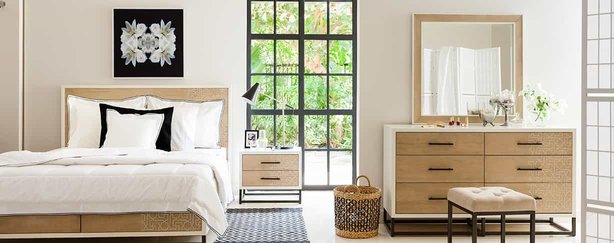 A modern bedroom with a large bed and a brown, wooden dresser.