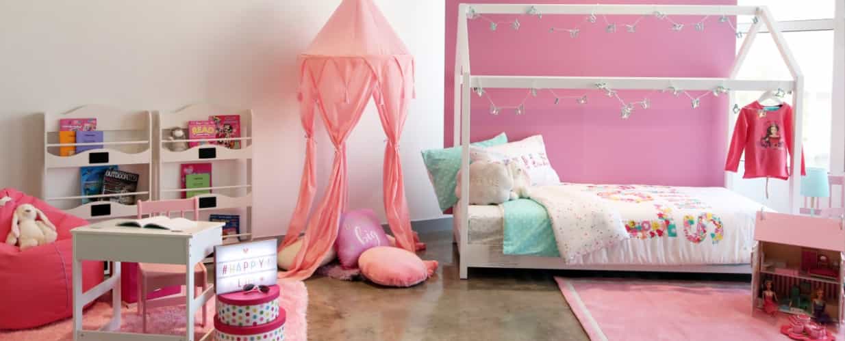 A pink kids' bedroom featuring a cute bed, a night stand and a shelf.