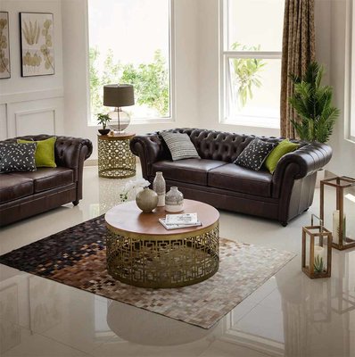 Living room with dark brown chesterfield sofas and round coffee table 