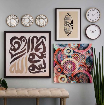 Three works of calligraphic and abstract art grouped together along with decorative wall plates and clocks 